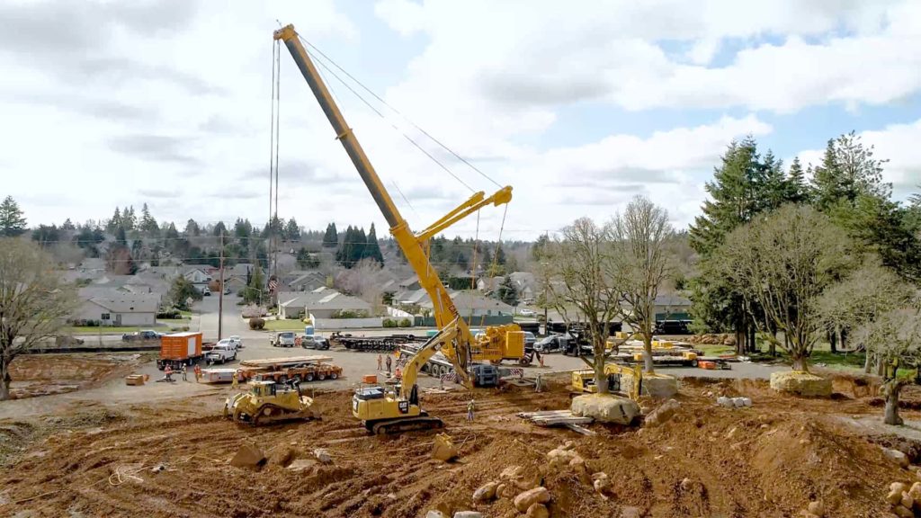 A crane lifting a large pile of dirt at a construction site | Crane Rental Services | NessCampbell