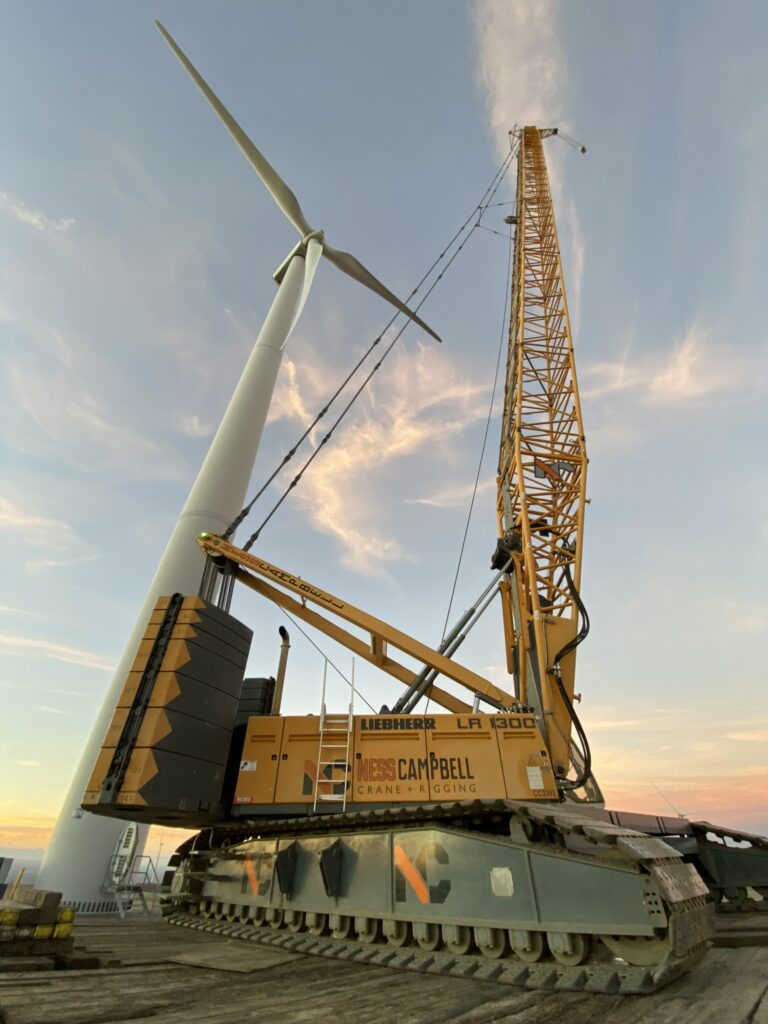 A crane perched on a dock beside a wind turbine | Crane Rental Services | NessCampbell