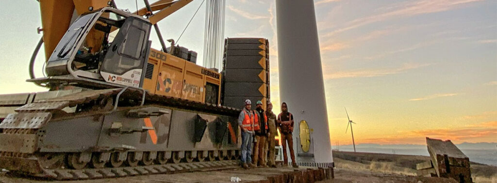 Construction worker stands beside a wind turbine | Crane Rental Services | NessCampbell