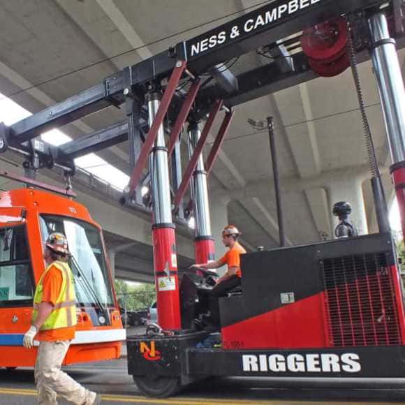 A man standing next to a crane lifting a bus | Crane Rental Services | NessCampbell