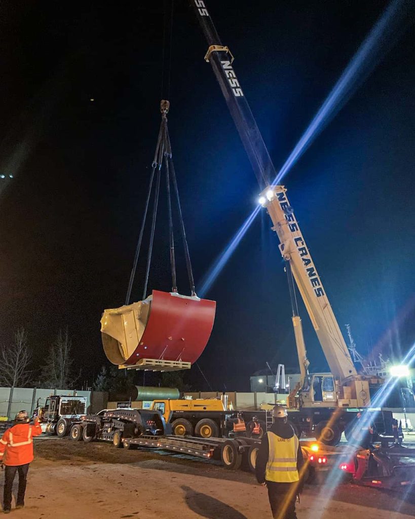 A crane hoisting a big red object onto a truck | All Terrain Crane | NessCampbell